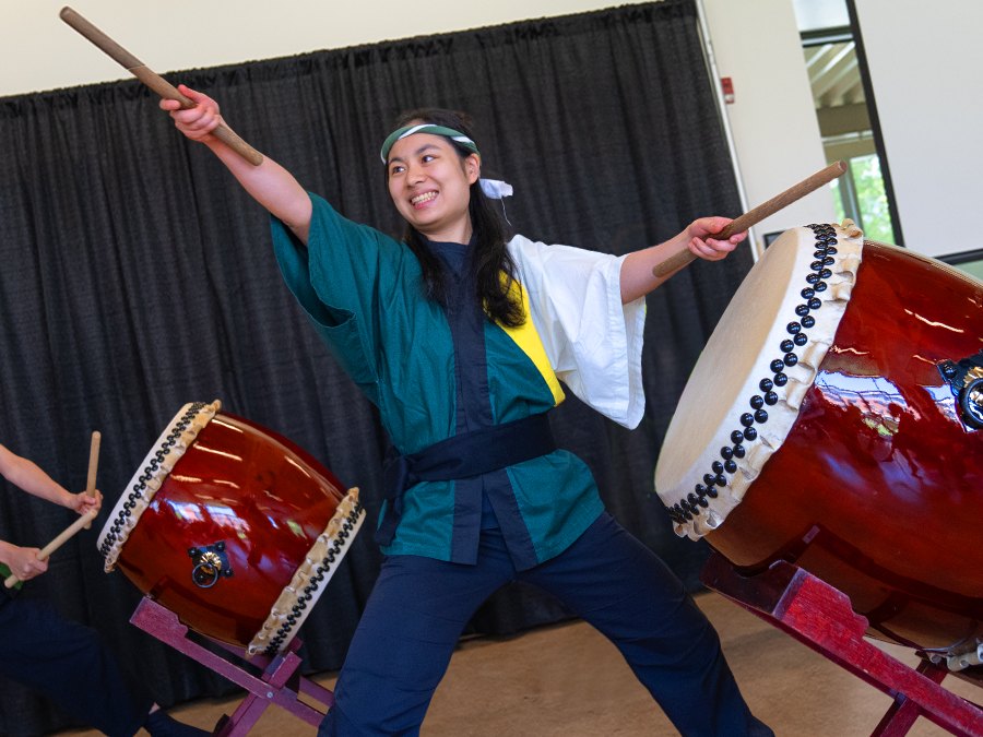A person raises drumsticks between two large taiko drums.