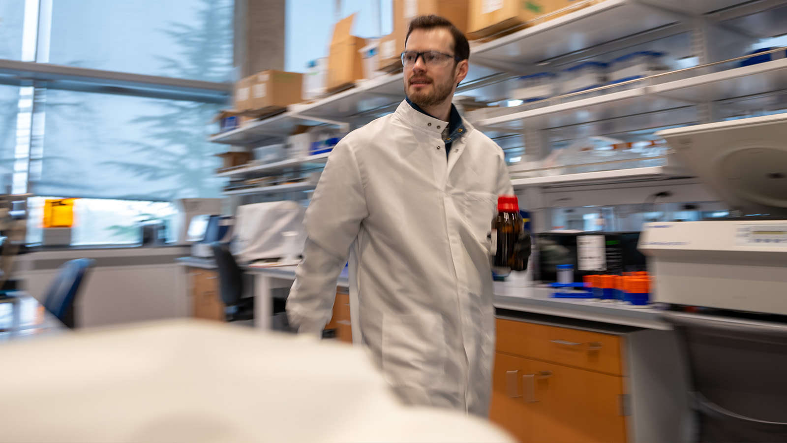 student walking through lab carrying samples