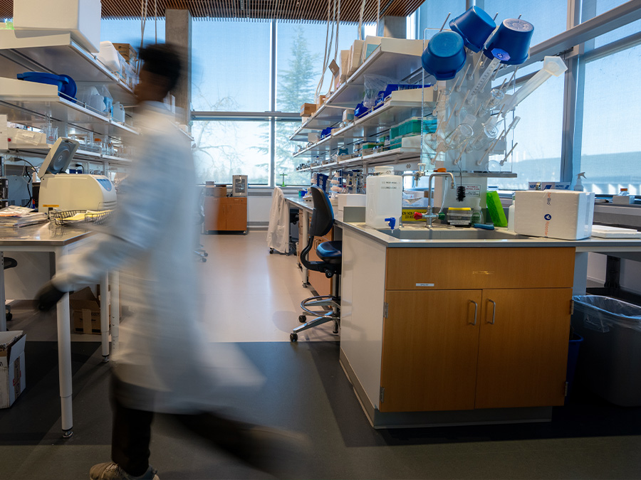 Researcher in a lab coat walking through a laboratory