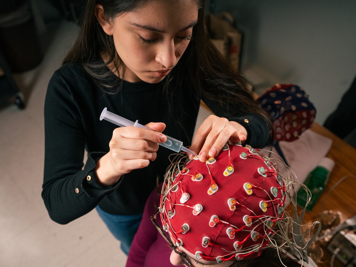 A researcher adjusts electrodes on an EEG cap.