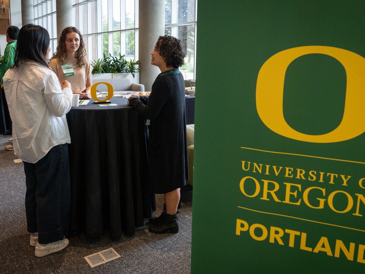 People talk beside a University of Oregon Portland sign.
