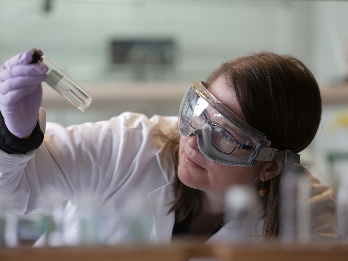 A researcher in safety goggles examines a laboratory sample.