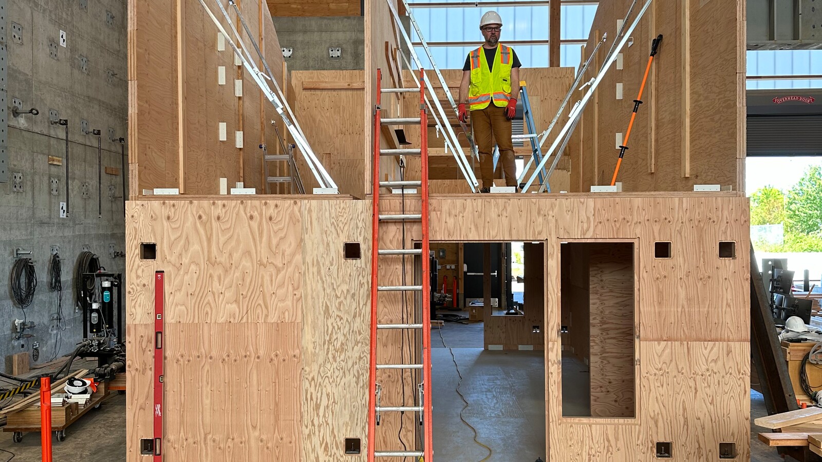 Workers assemble a mass-timber housing prototype indoors.