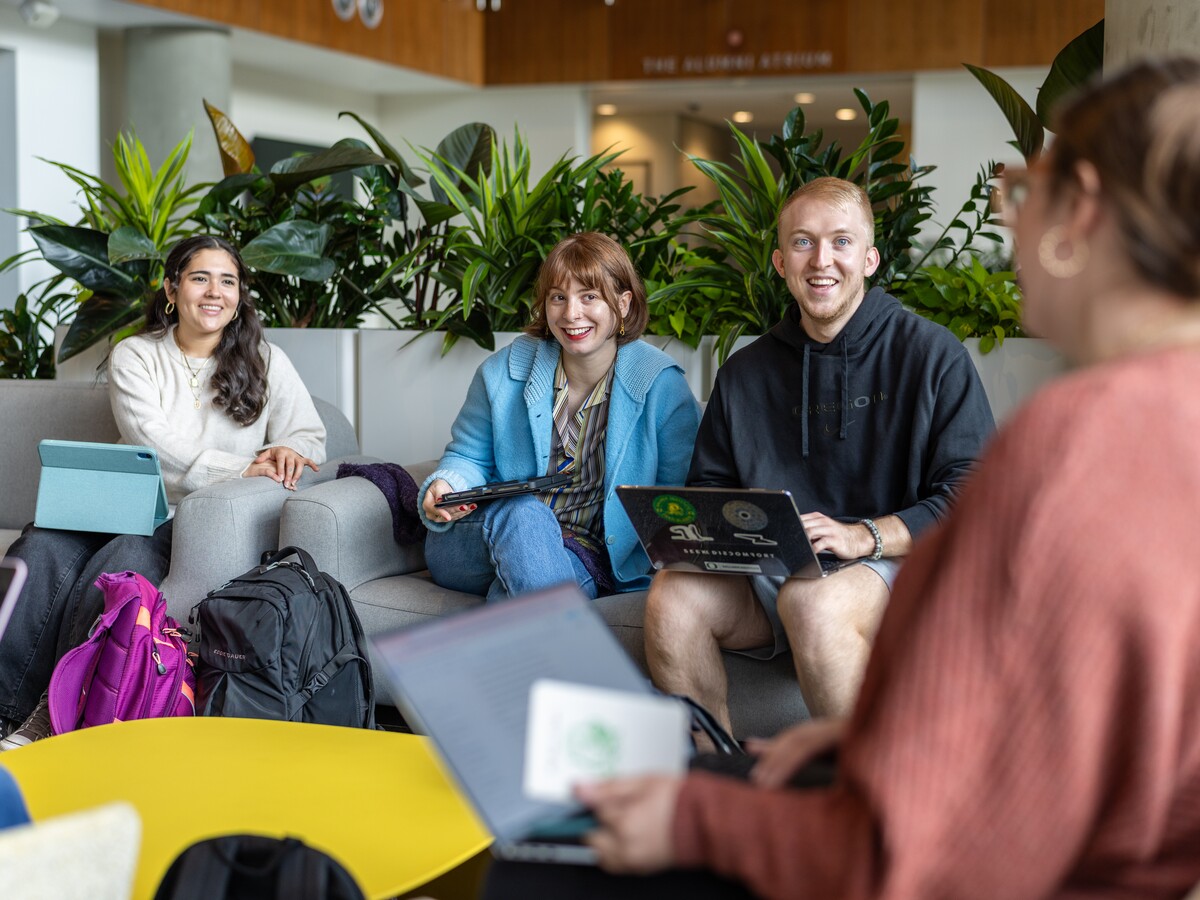 Four people talk together in a bright lounge.