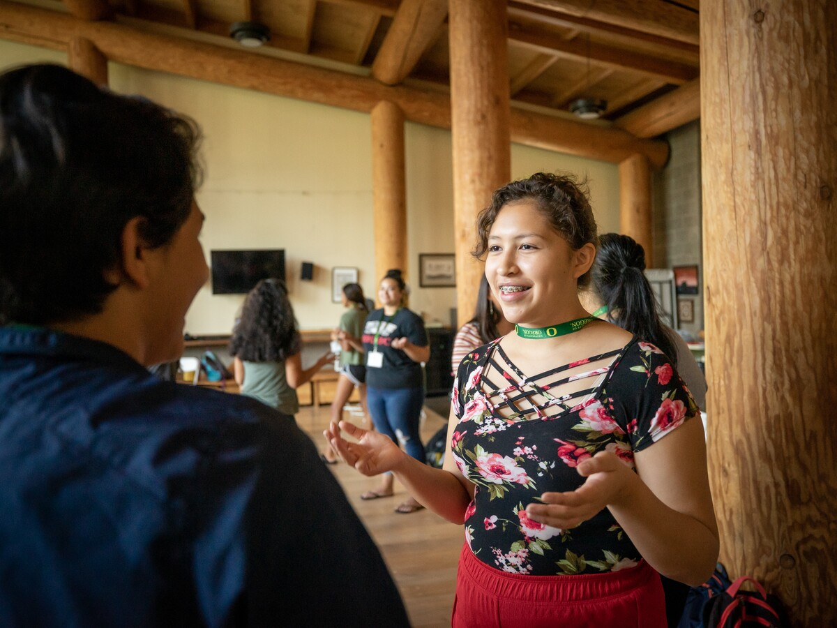 A speaker addresses a small group inside a wooden gathering space.