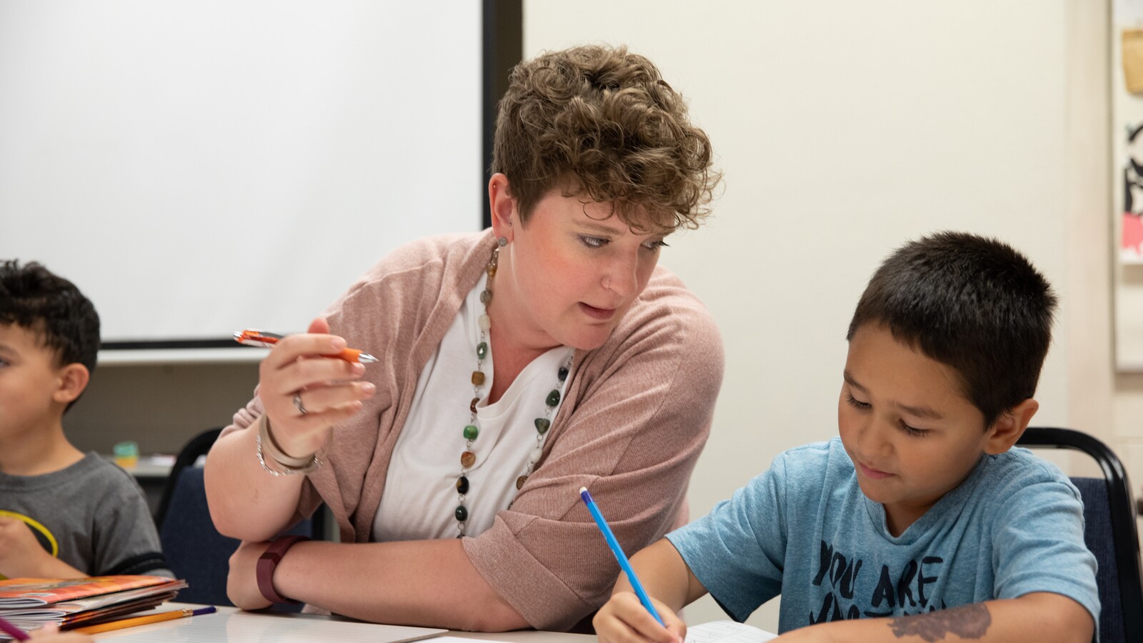 An adult helps a child with a classroom activity.