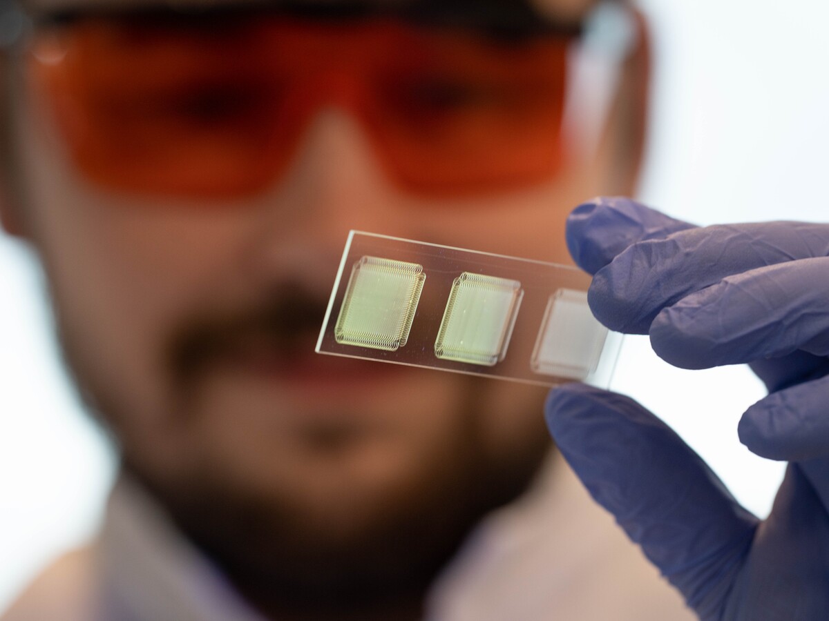 A gloved hand holds two small electronic sensors.