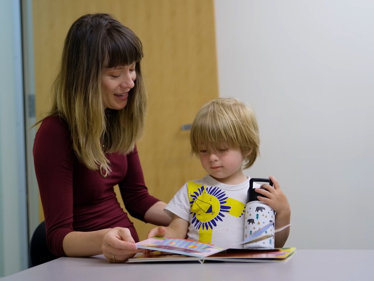 An adult guides a child through a tabletop activity.