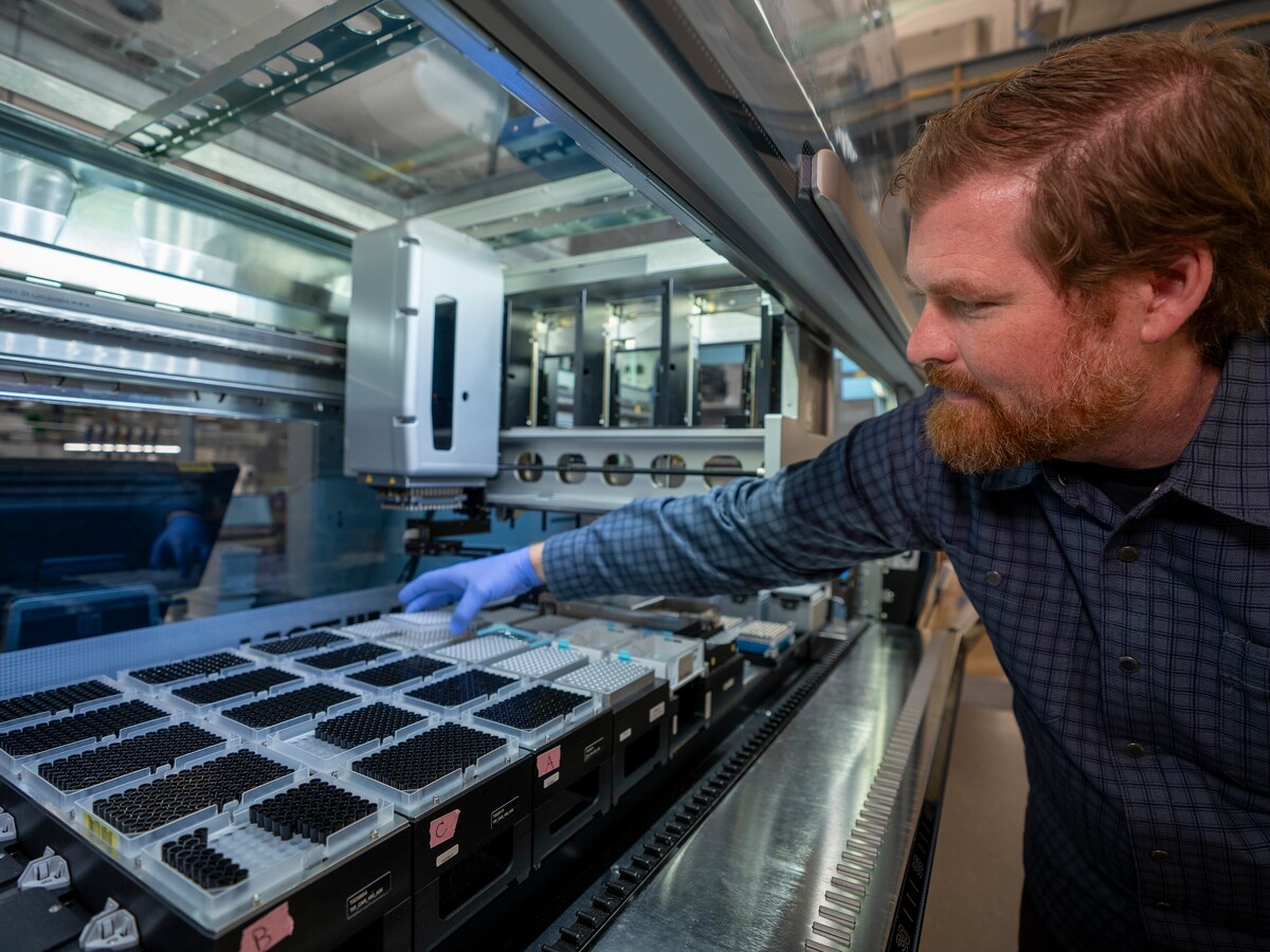 A researcher loads sample trays into laboratory equipment.