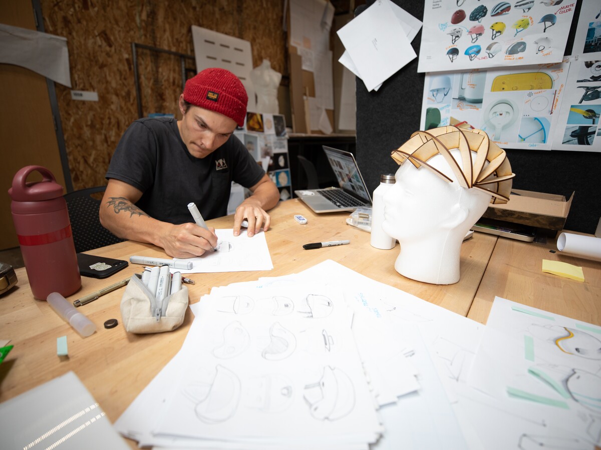 A product design student sketches beside a prototype.