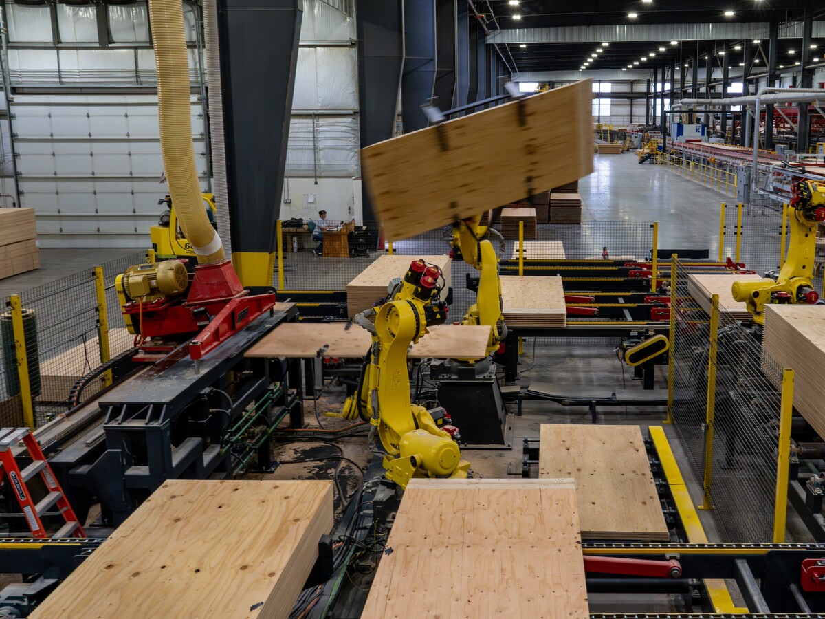 Robotic equipment assembles mass timber panels in a factory.
