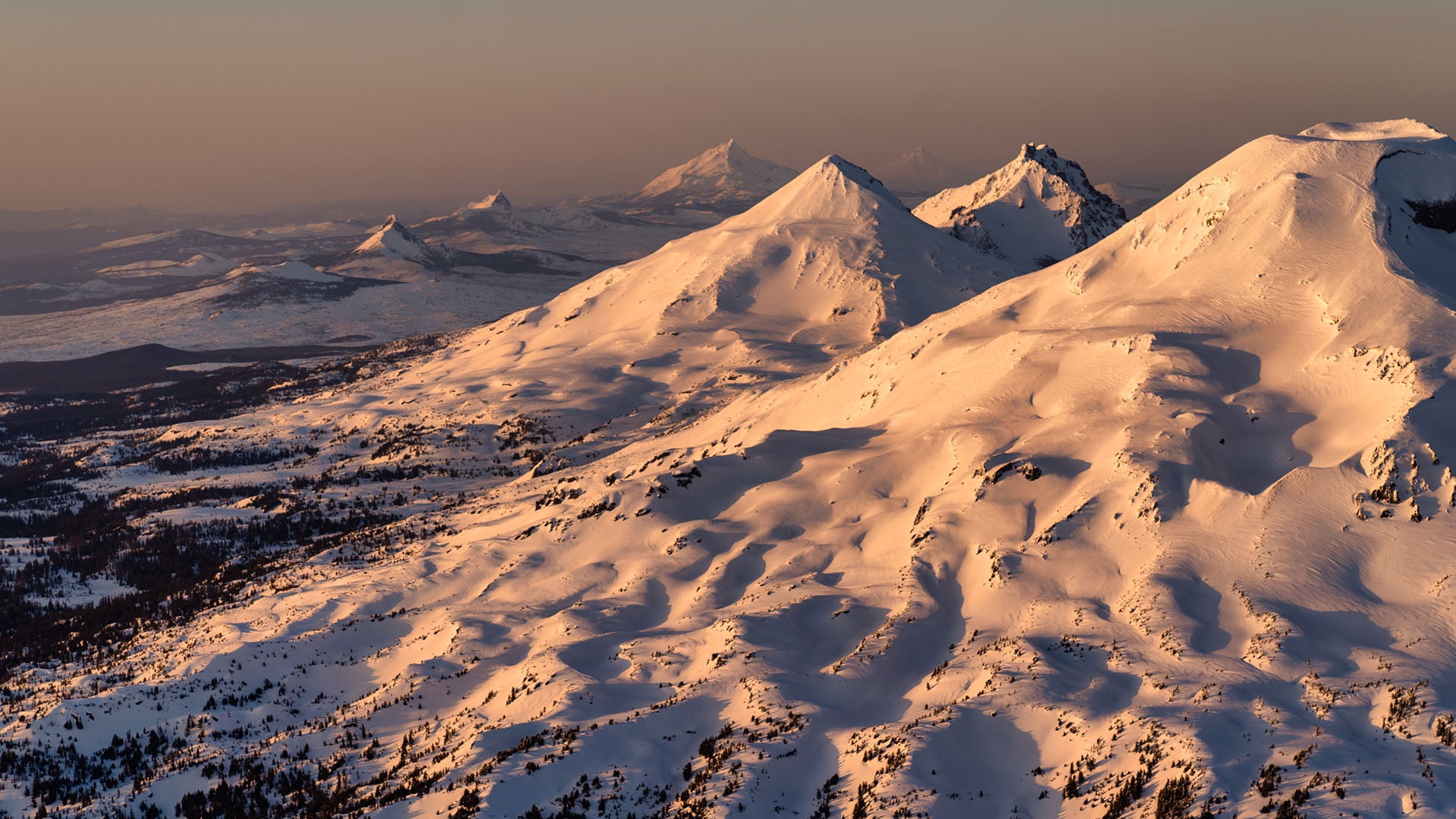 Snow-covered Cascade peaks glow at sunset.
