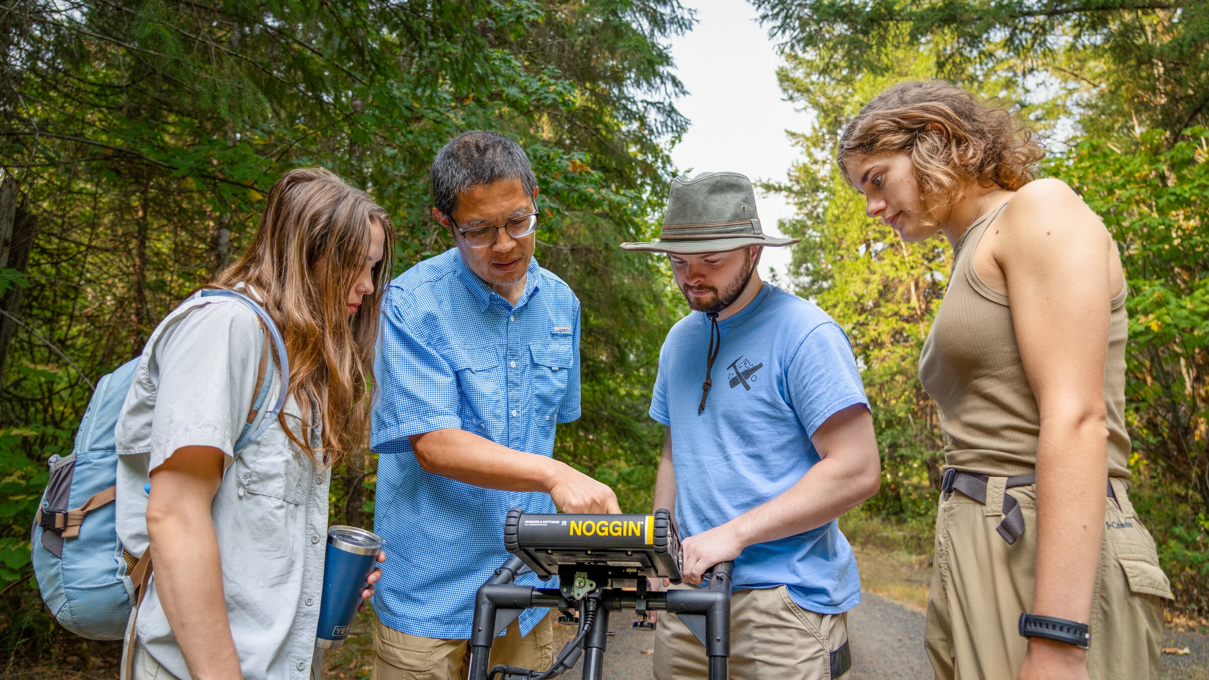 Four researchers examine monitoring equipment outdoors.