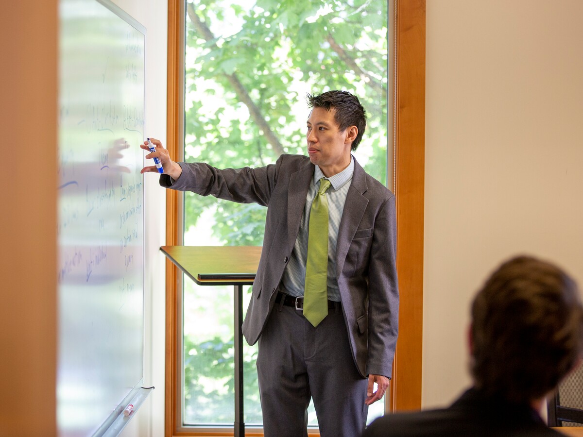 A faculty member leads a discussion at a whiteboard.