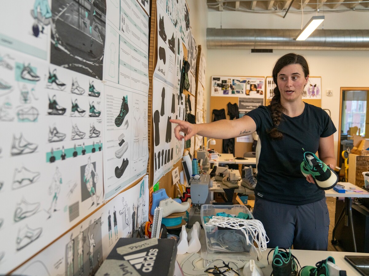 A designer points to footwear drawings in a studio.