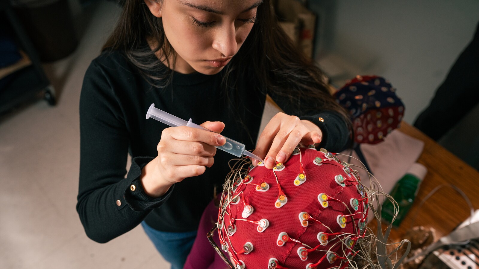 A researcher applies gel to electrodes on an EEG cap.