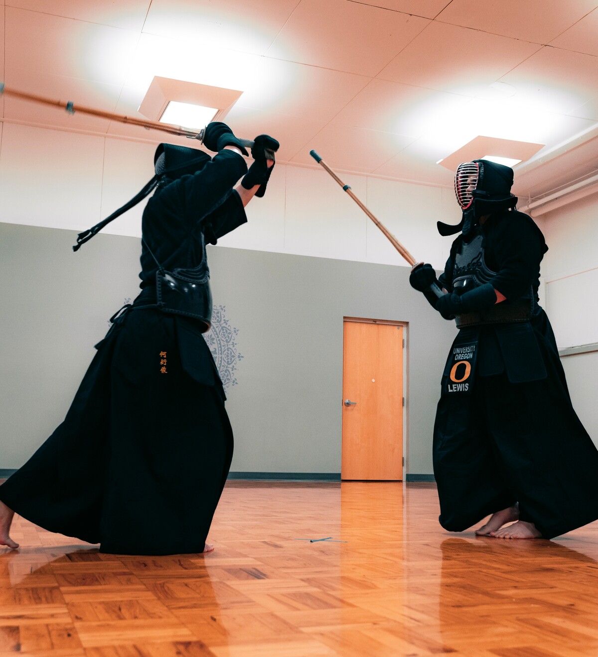 Two kendo club members practice in protective gear.