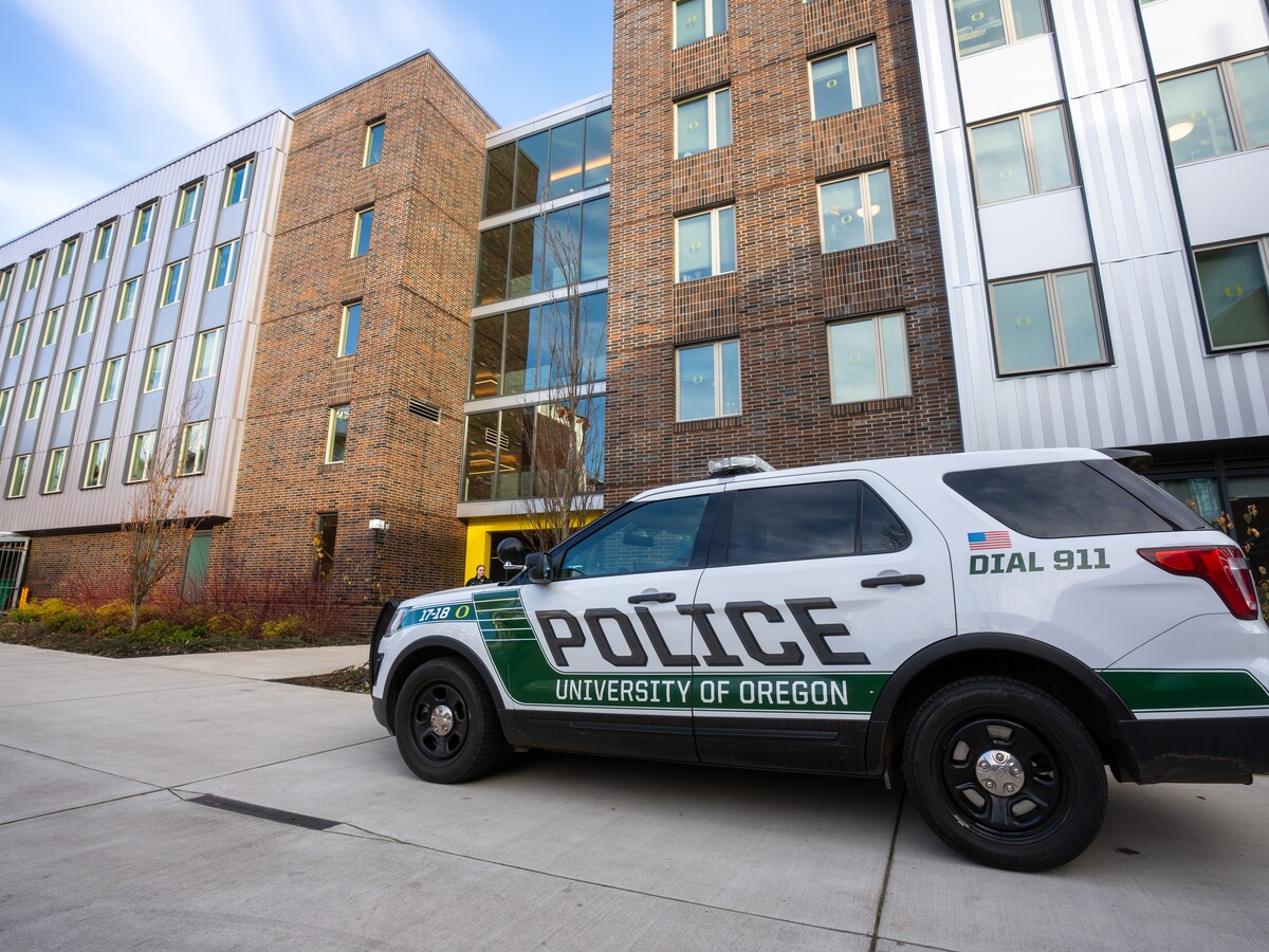 A University of Oregon Police vehicle is parked beside a campus building.