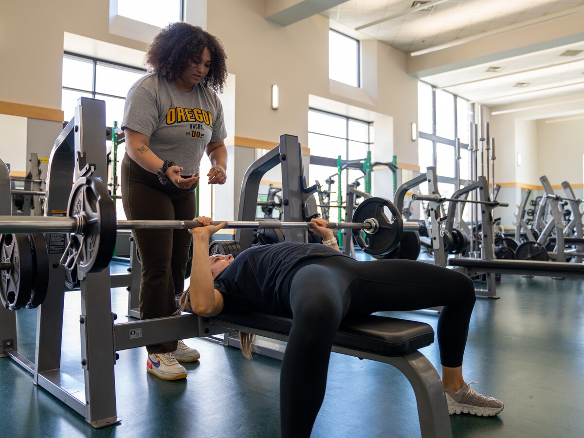 One person spots another during a bench press exercise.