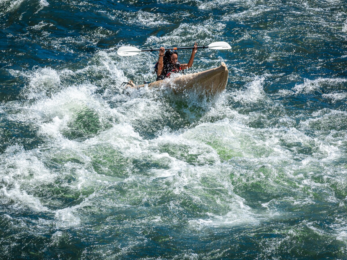 Students steer an inflatable raft through whitewater.