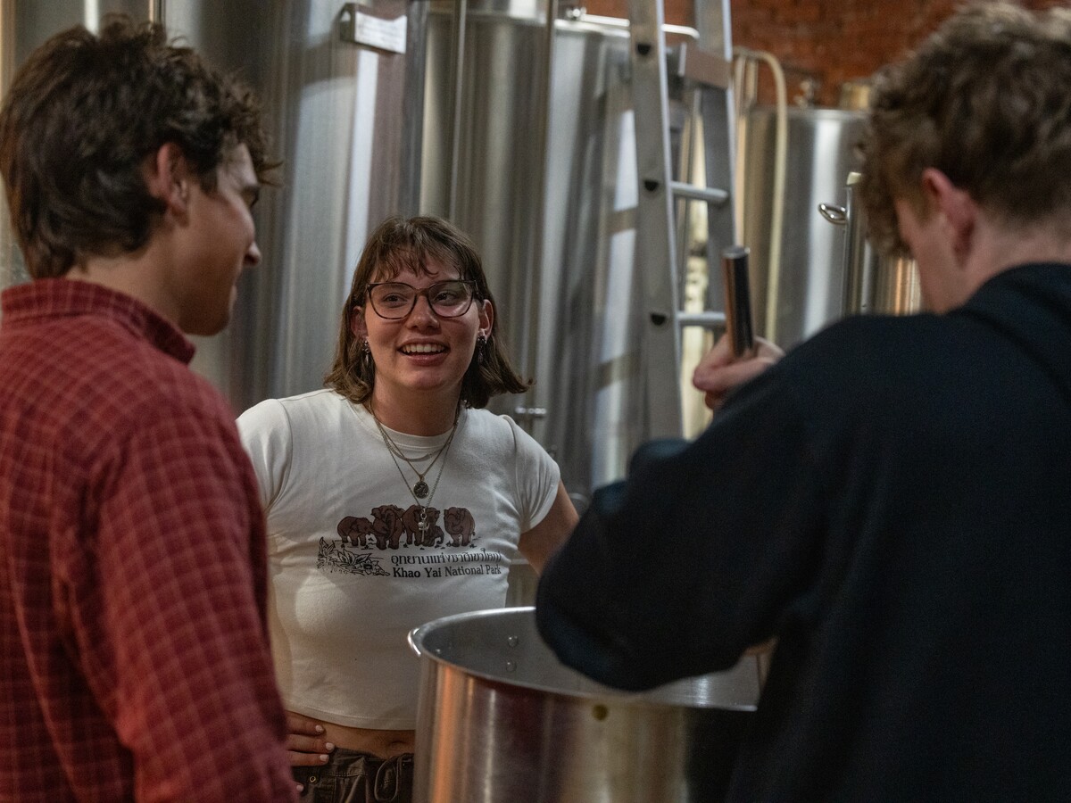 Three students work together with brewing equipment.