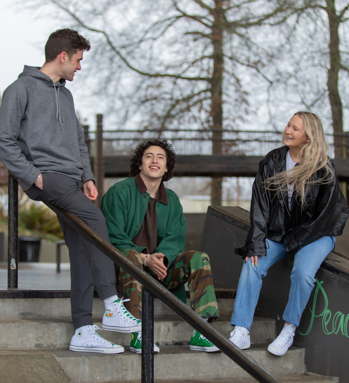 Three students talk at a campus skate park.