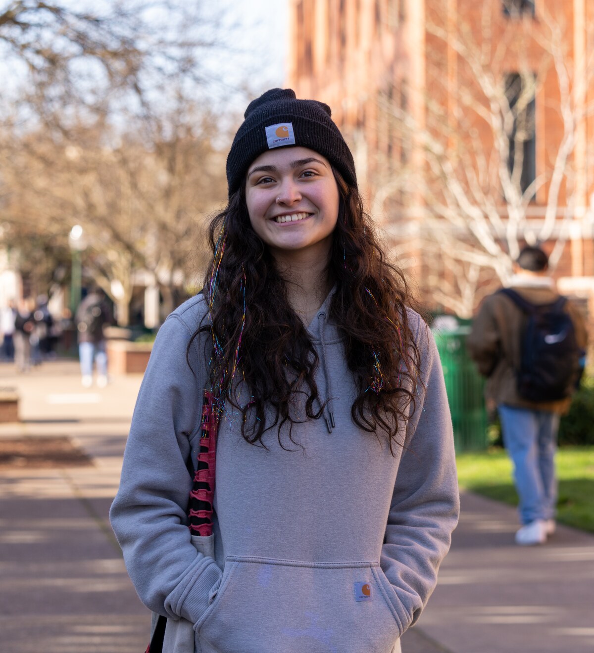 A student smiles outdoors on campus.