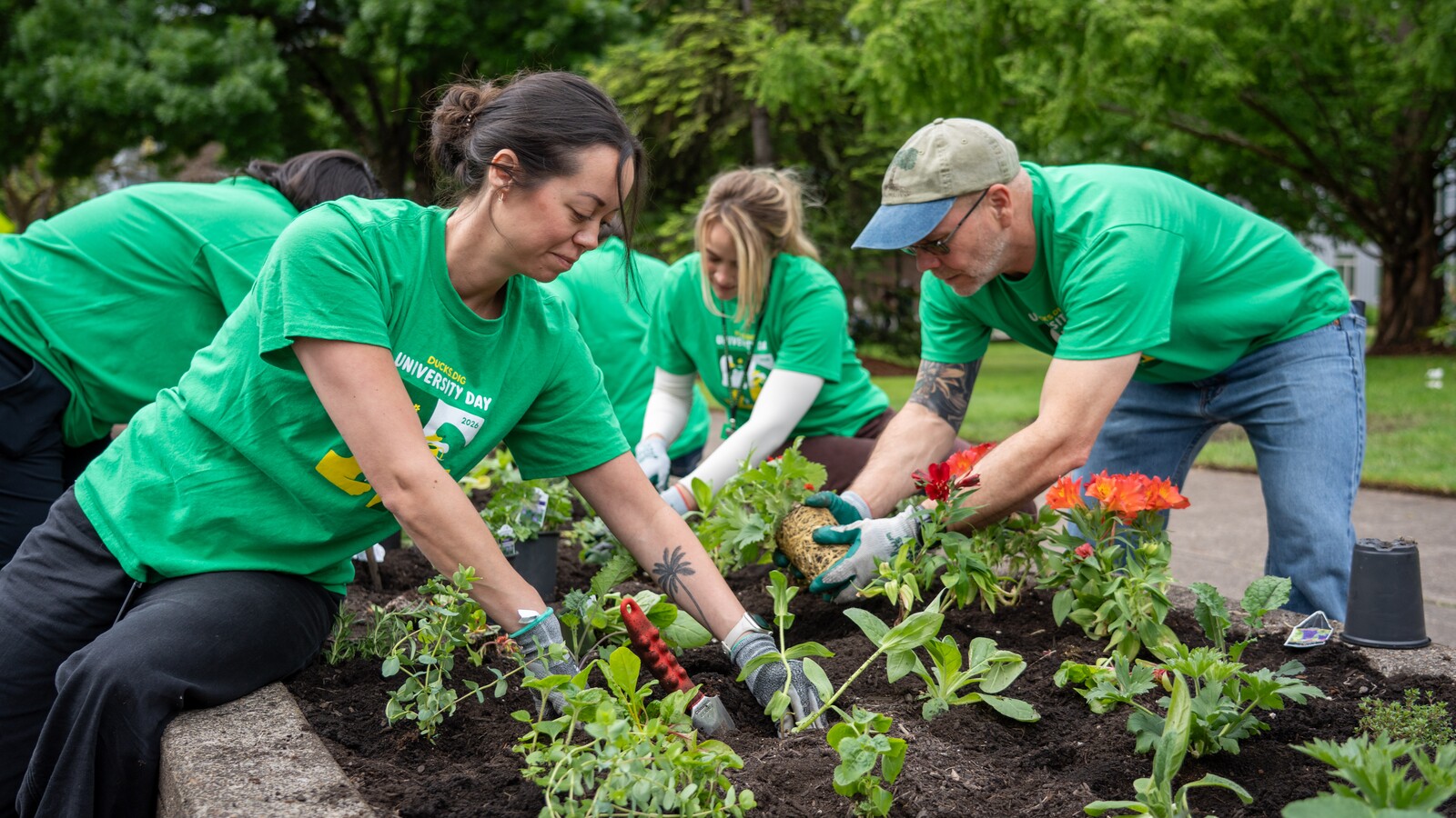 Volunteers plant flowers in a campus garden.