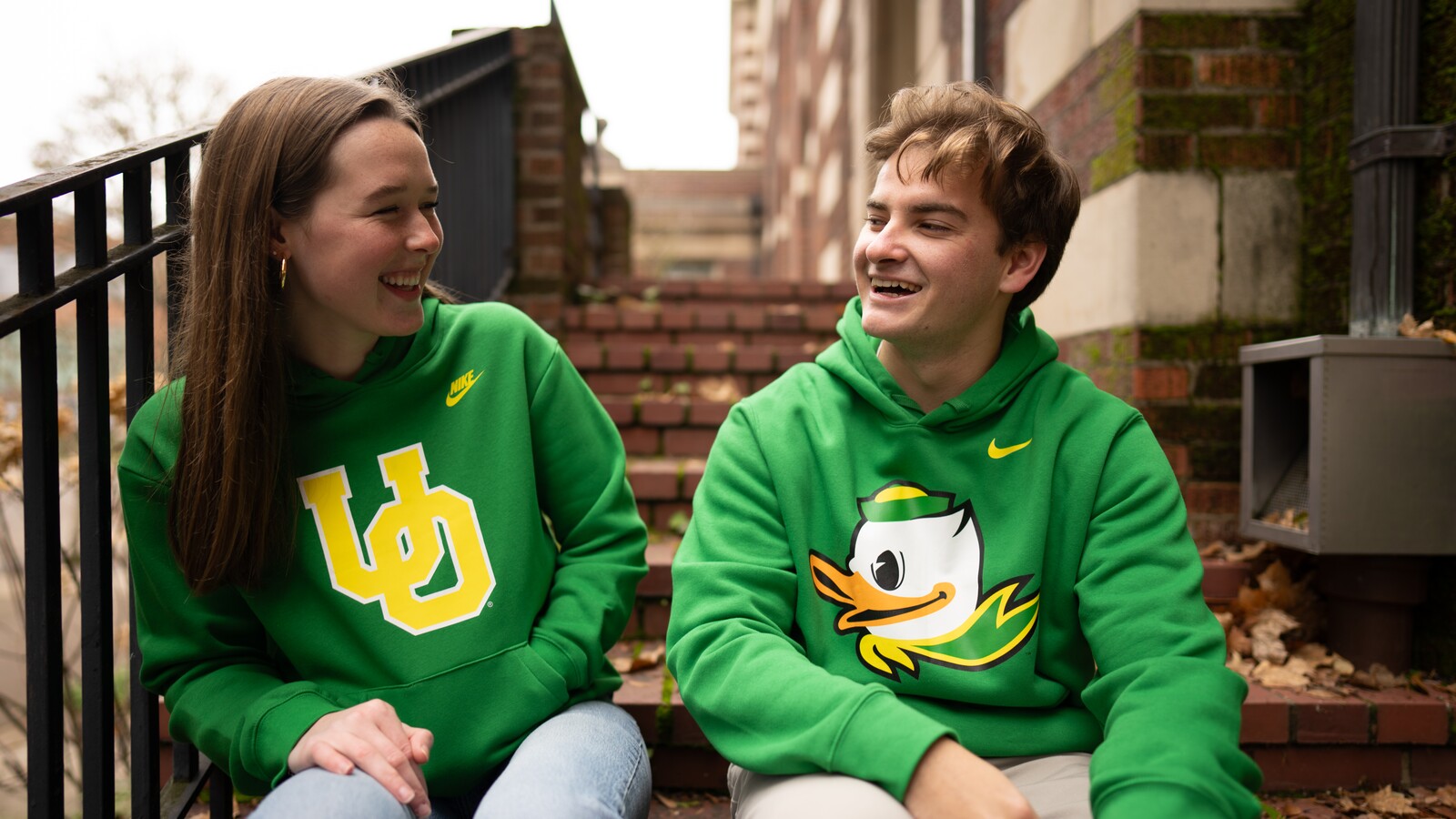 Two alumni wear Oregon sweaters outdoors.