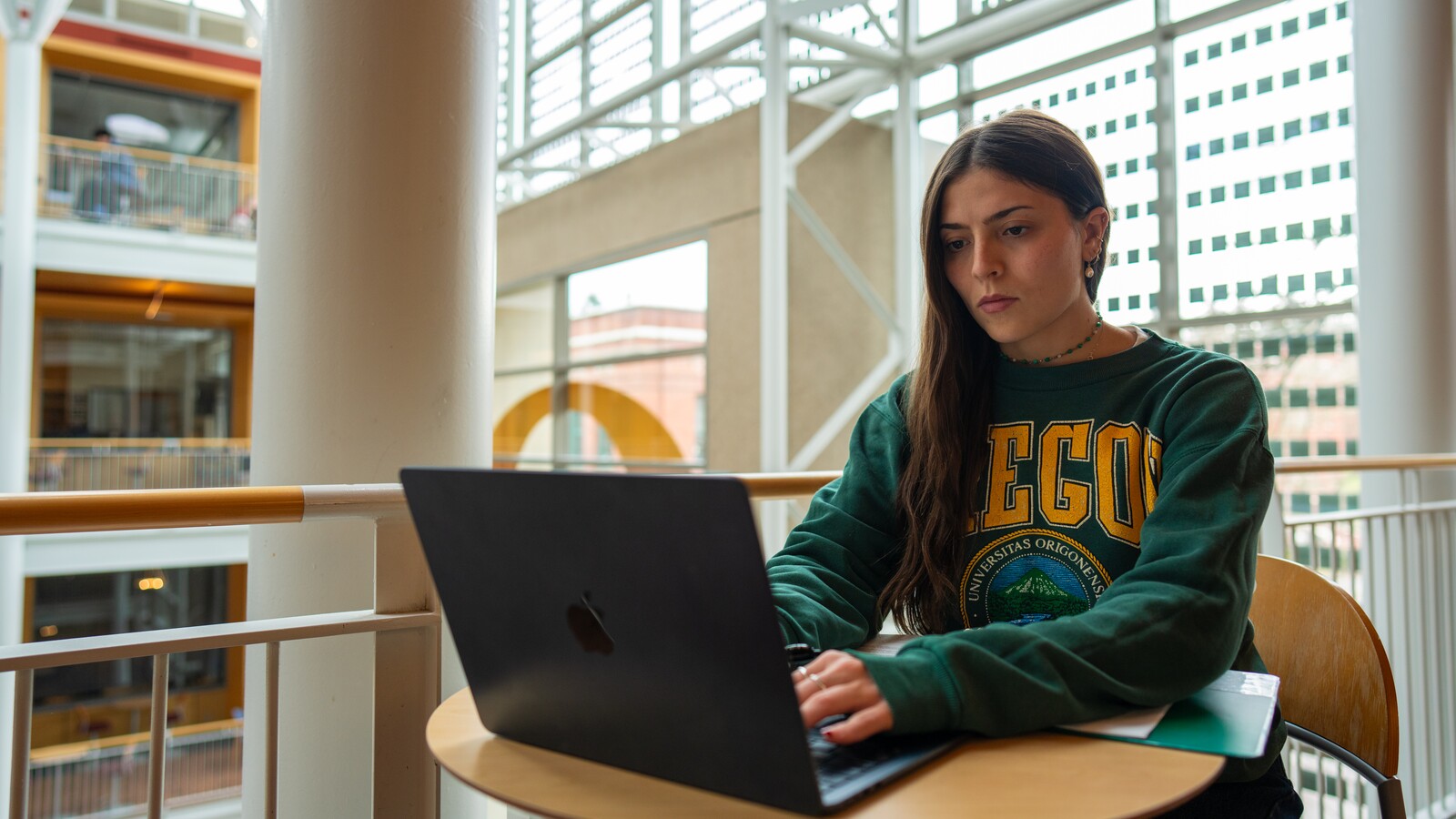 A student uses a laptop at a campus table.